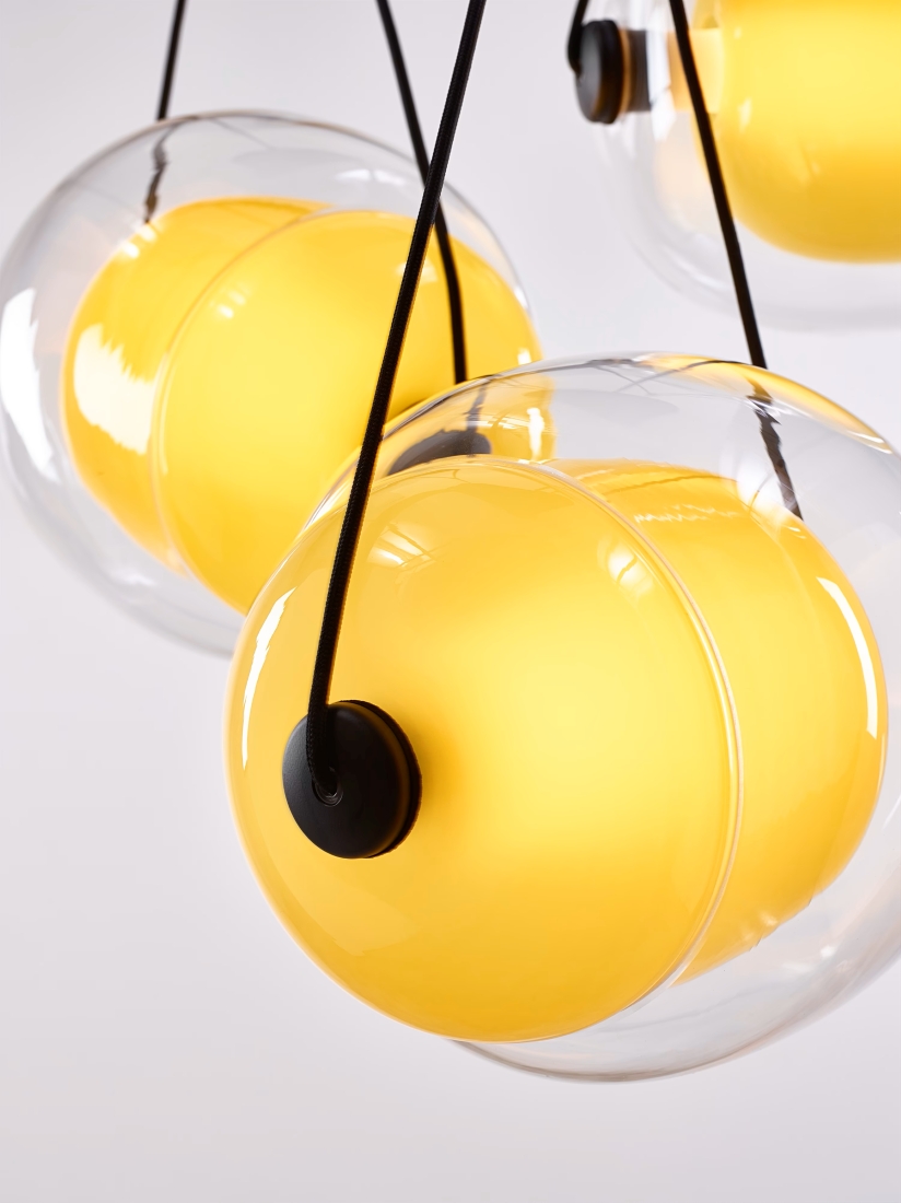 Brokis Capsula Triangle lights, handblown glass globes with vivid yellow centres, glow elegantly on black cords.