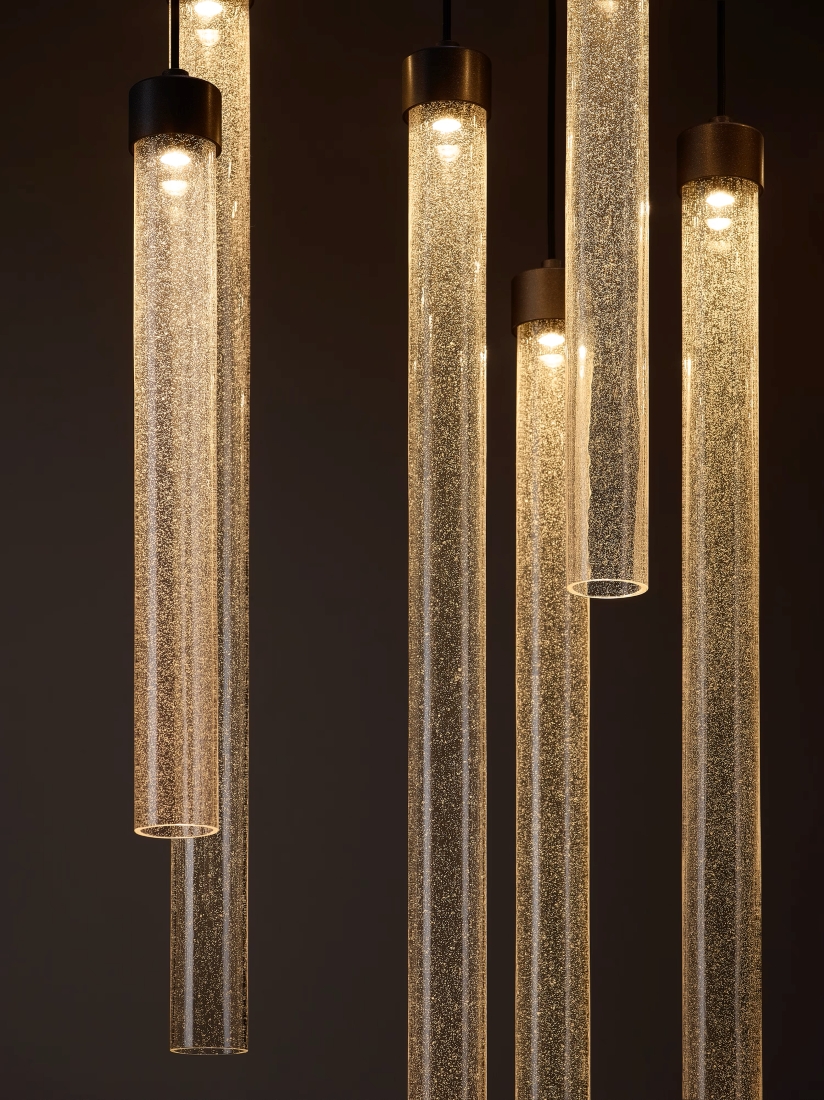 Brokis Comet Round pendants with silica emit a warm glow, illuminating a dark space with sculptural luxury.
