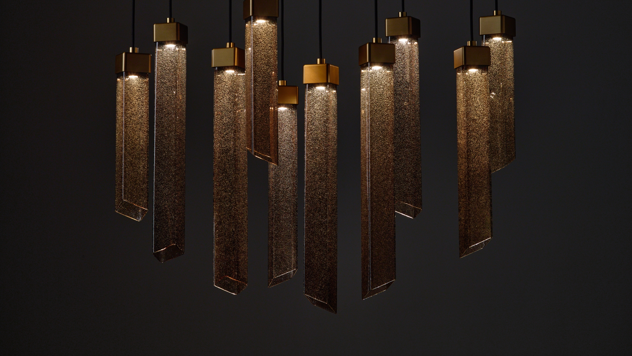 A cluster Brokis Comet Square pendants in smoke brown glass glows warmly, exuding refined luxury.