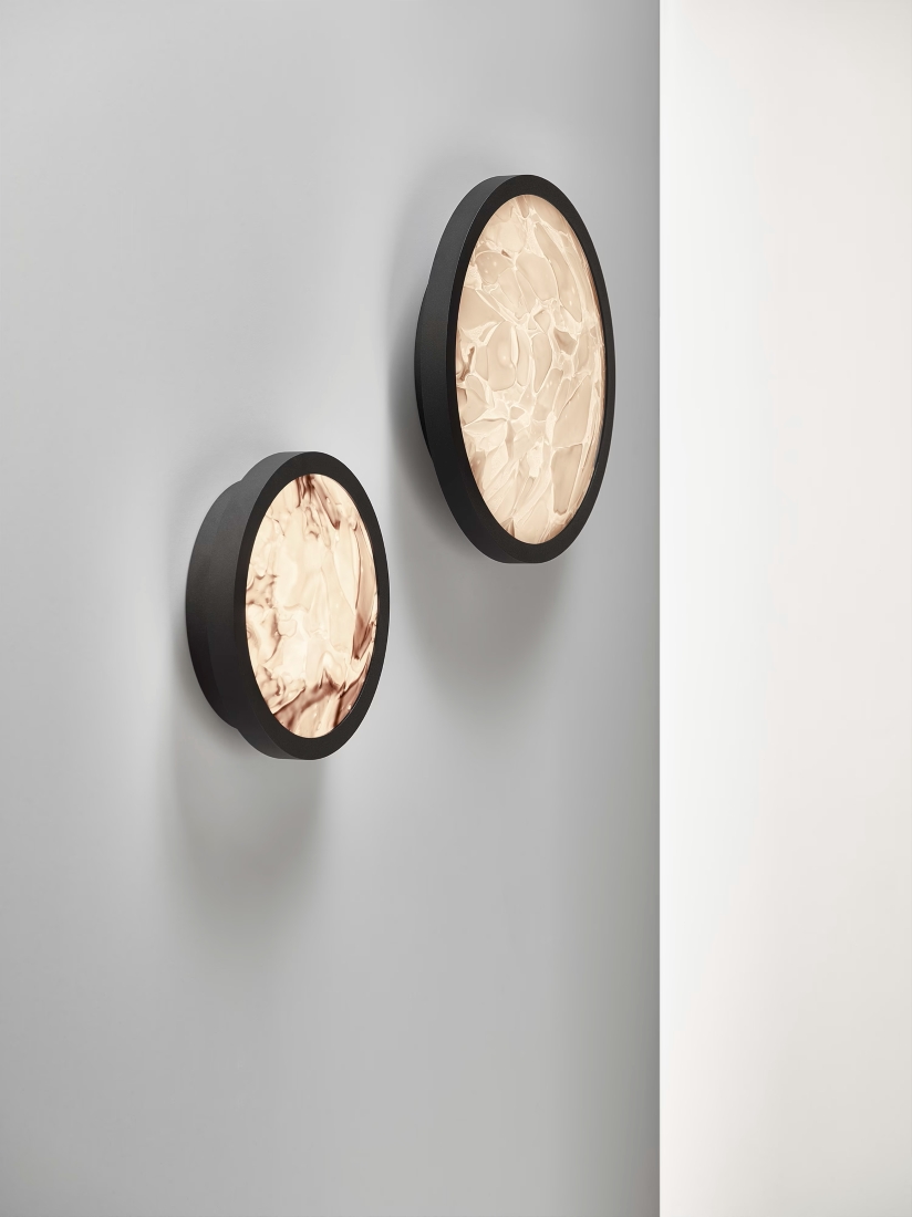 Brokis Convex Appliques wall lamps in textured BROKISGLASS cast a warm glow on a light grey wall, exuding modern luxury.