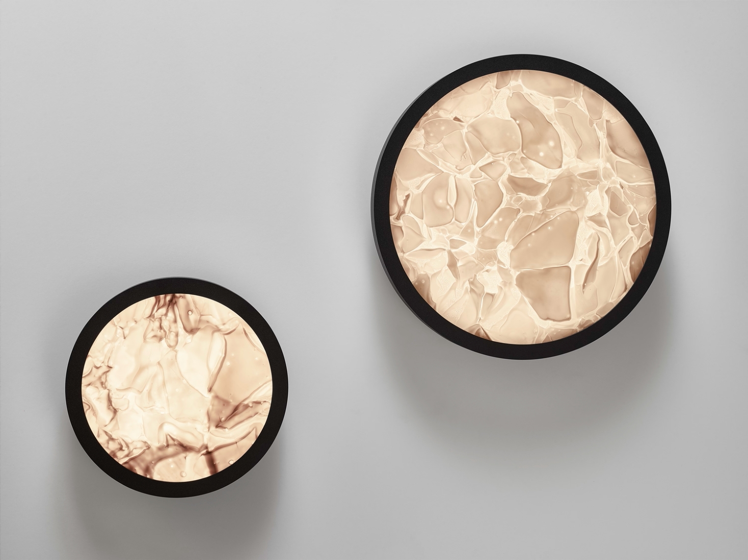 Two Brokis Convex wall lights with black frames and BROKISGLASS faces glow elegantly against a white wall.