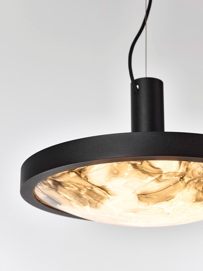 Brokis Convex M Pendant with a circular black frame and BROKISGLASS diffuser glows warmly from elegant black cables.