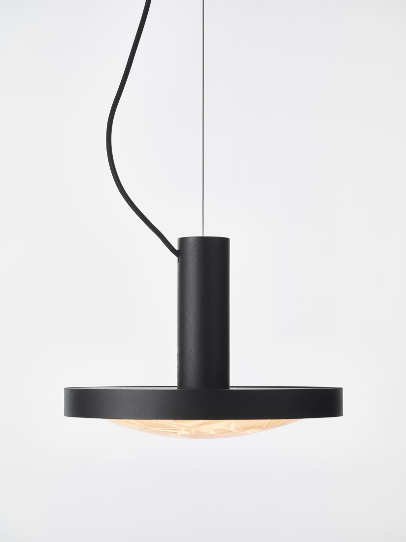 Brokis Convex S Pendant floats from a slender cord, its handblown cylindrical body glowing against a pristine white backdrop.