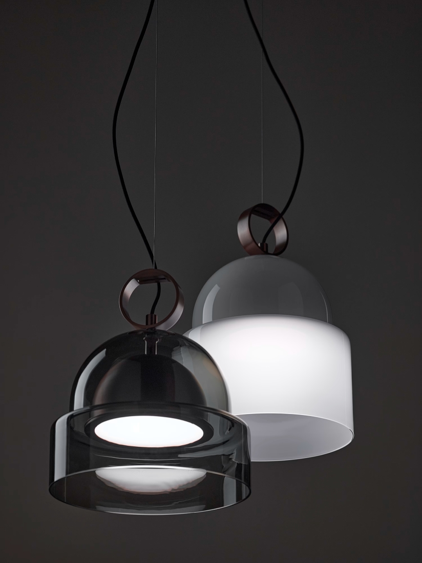 Two Brokis Dome Pendants with clear and opaline hand-blown glass shades emit a soft glow against a dark backdrop.