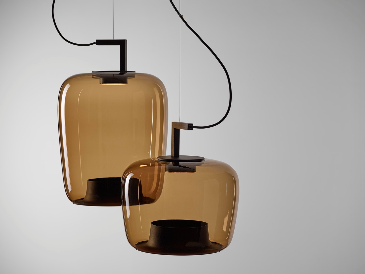 Brokis Double pendants in handblown brown glass hang at varied heights, accented by sleek black fittings.