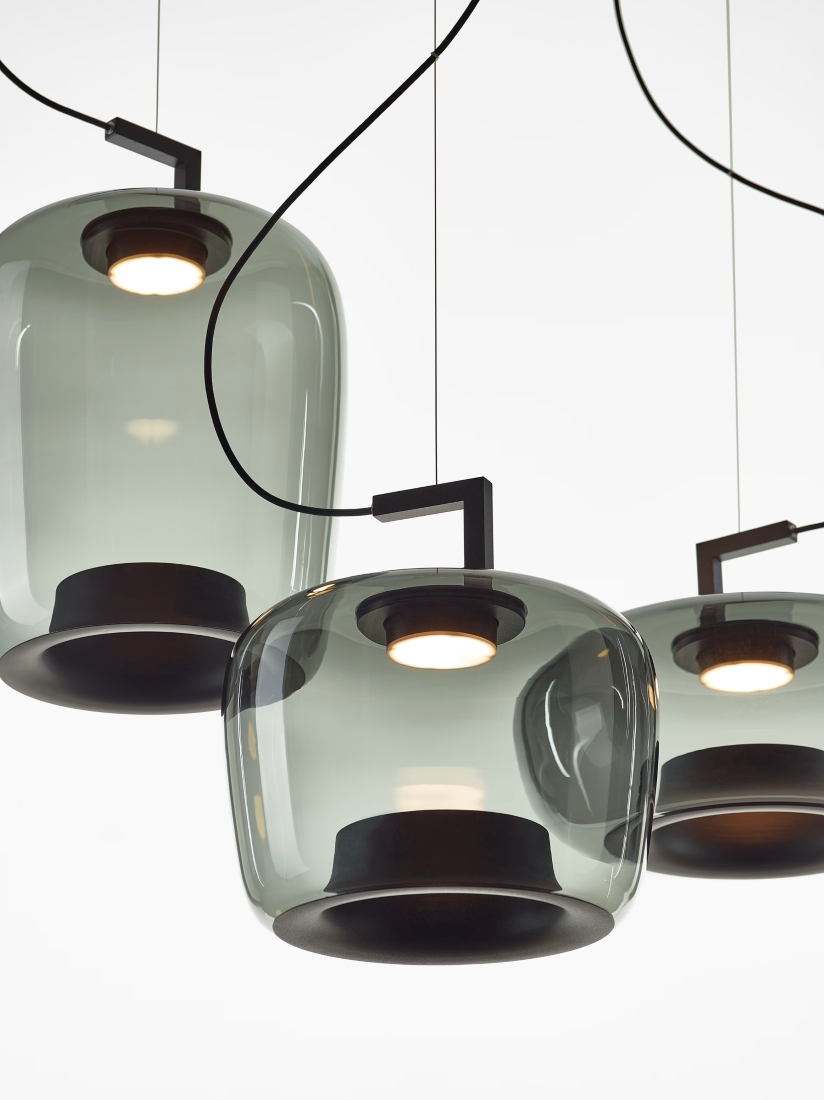 Brokis Double pendants in smoke grey handblown glass with black accents glow warmly, exuding refined luxury.