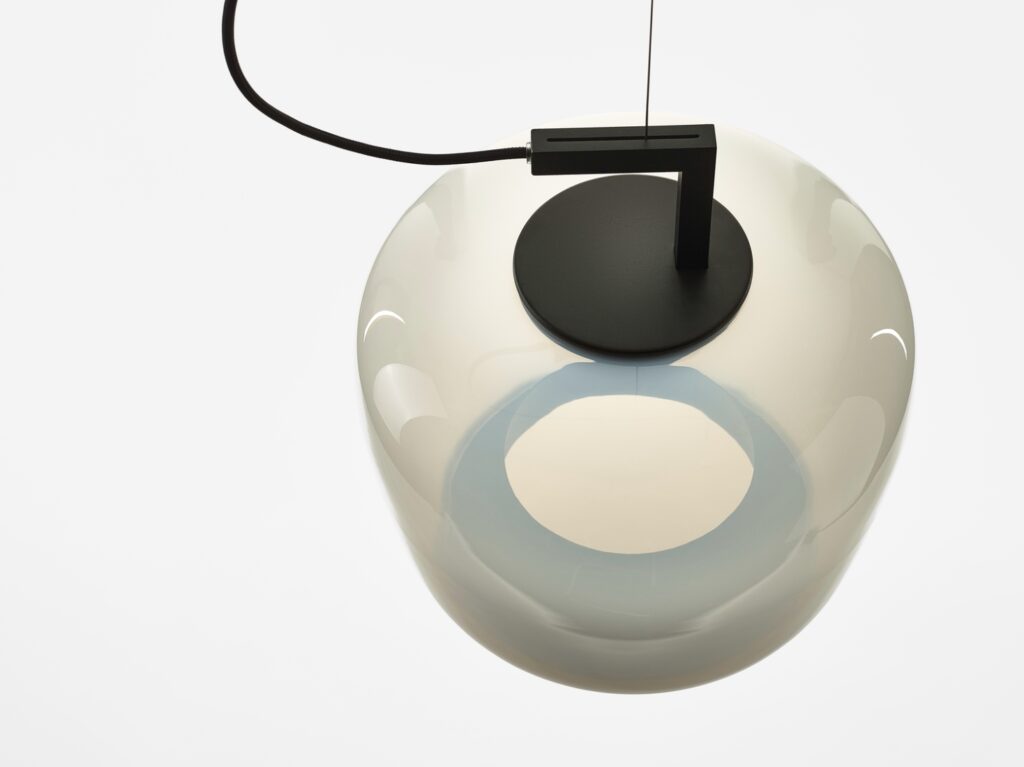 Brokis Double Medium Pendant, handblown and rounded, hangs elegantly from a black cable against a white backdrop.