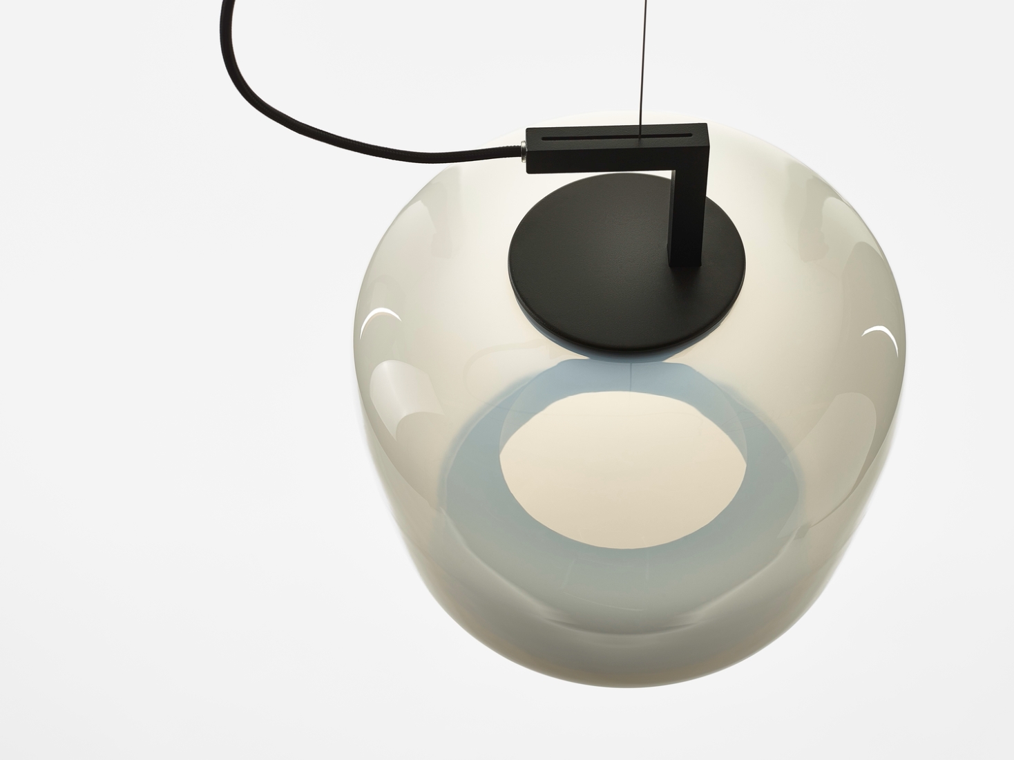 Brokis Double Medium Pendant, handblown and rounded, hangs elegantly from a black cable against a white backdrop.