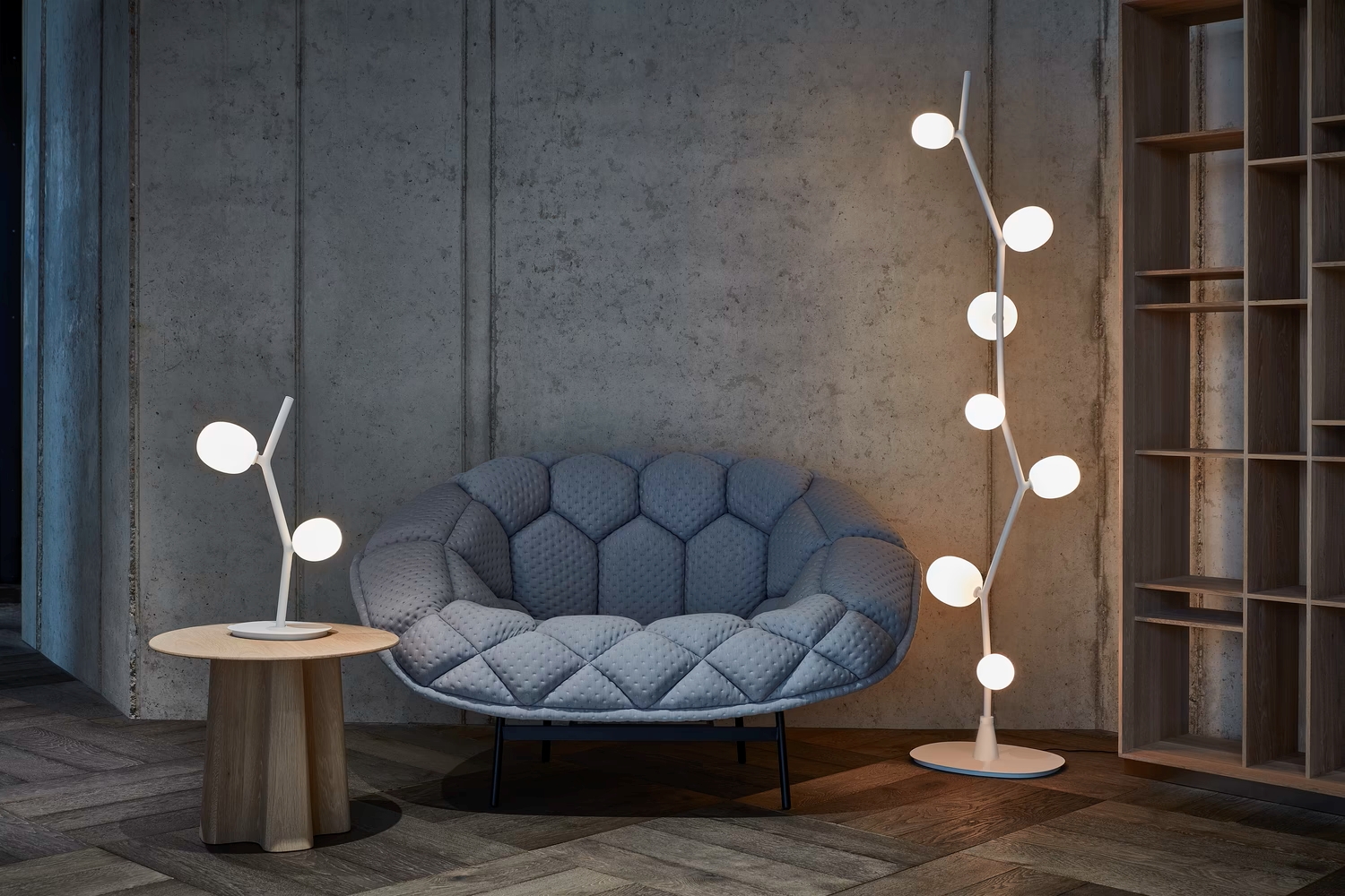 Luxurious living space with a round grey armchair, wooden side table, and Brokis Ivy table and floor lamps aglow.