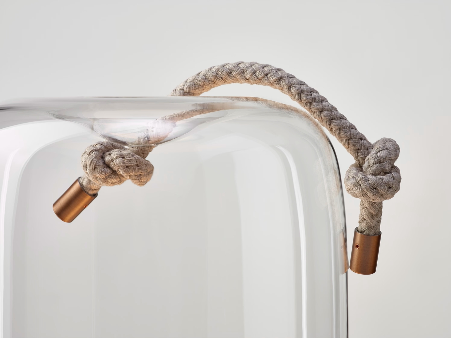 A thick, plaited beige rope with copper ends is knotted and draped over the rounded rim of Brokis Knot Cilindro Table,