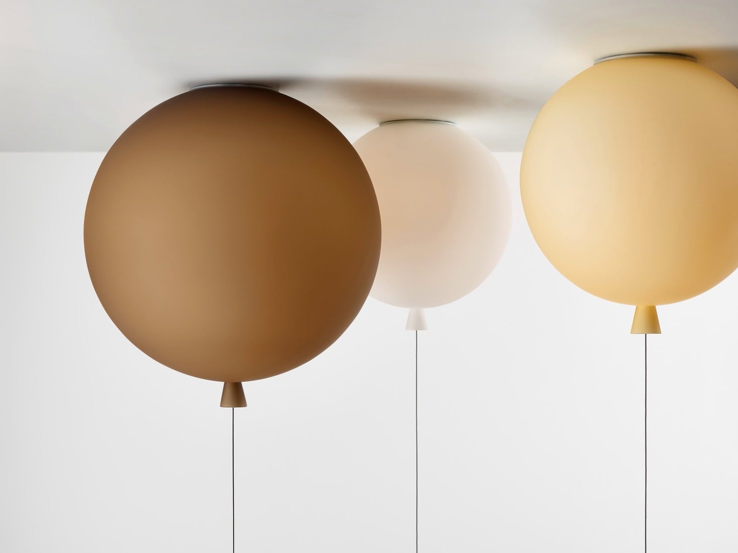 Brokis Memory ceiling lights mimic helium balloons in brown, white, and amber with elegant trailing strings.