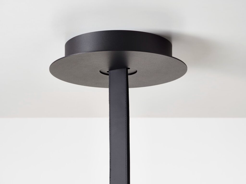 A close-up of a Brokis Mona ceiling canopy with a matt black base and leather, accenting the luxurious, minimal décor.