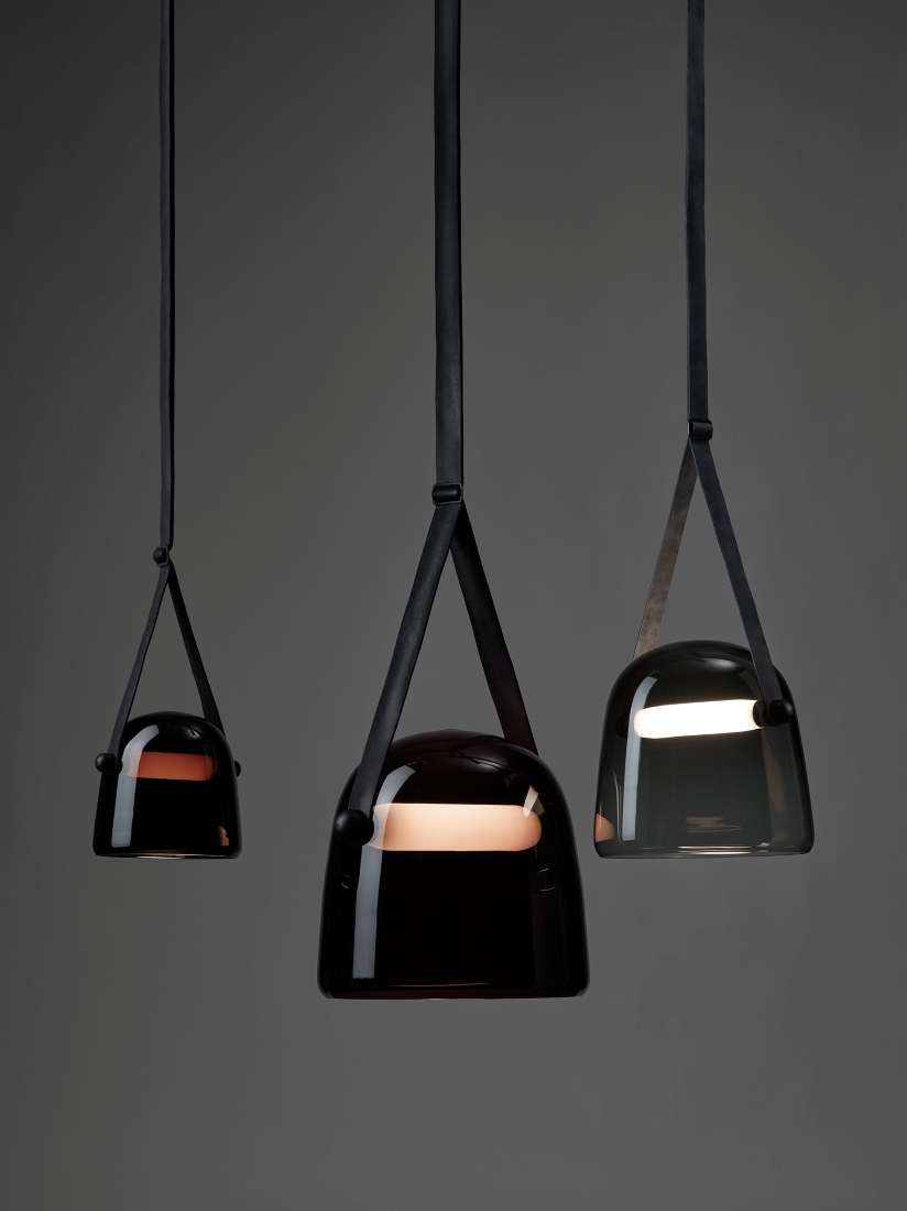Brokis Mona Pendants with handblown glossy black shades hang at varying heights against a moody charcoal backdrop.
