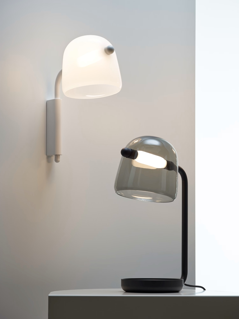 A minimalist room with Brokis Mona Wall glass lamps emits a soft glow, epitomising refined modern luxury.