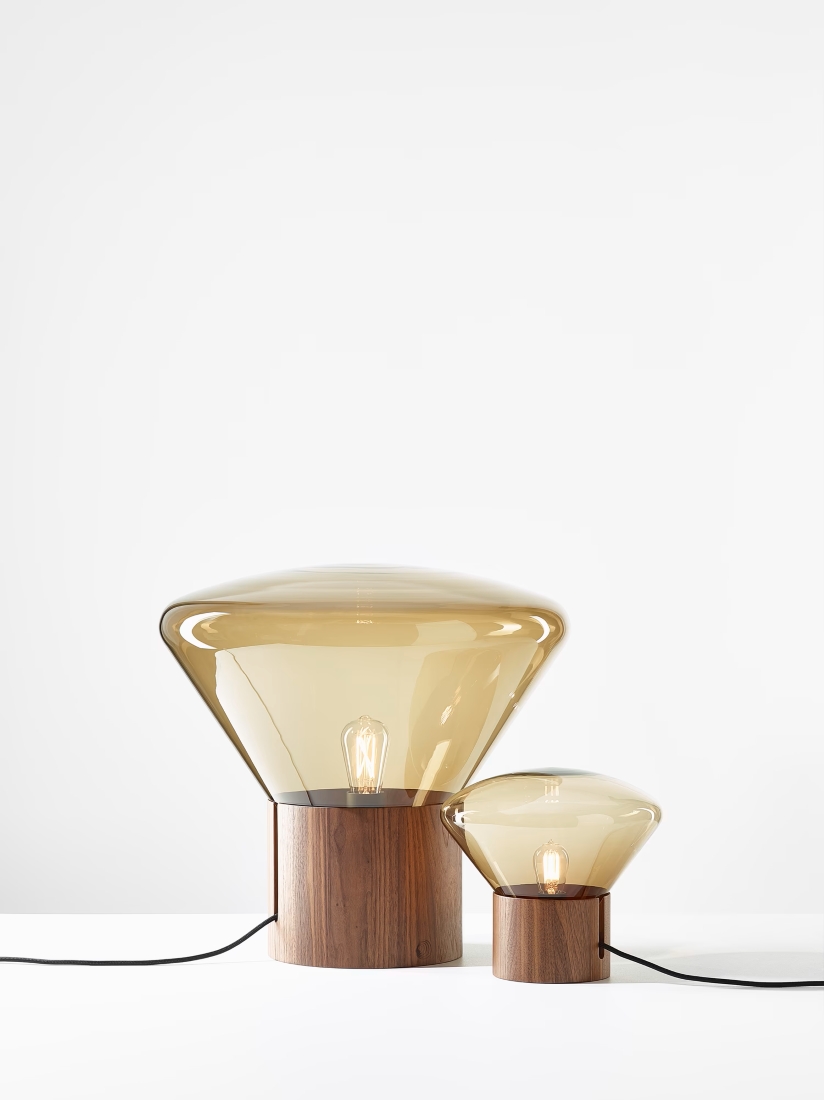 Two Brokis Muffins table lamps with handblown brown glass shades and wooden bases sit elegantly on a pristine white surface.