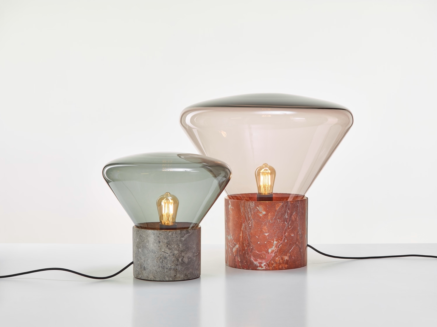 Brokis Muffins lamps with hand-blown glass shades and marble bases exude luxury on a pristine white surface.