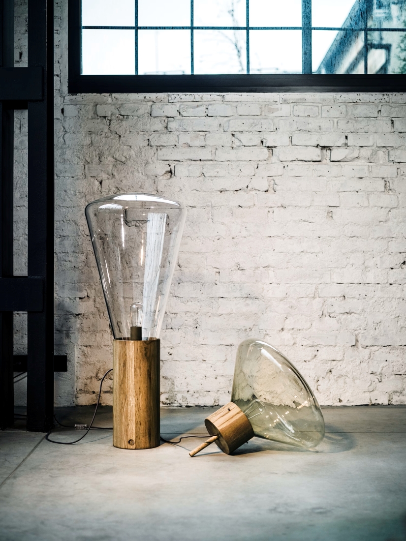 Brokis Muffins floor lamps with wooden bases accent a concrete floor, bathed in natural light by a tall window.