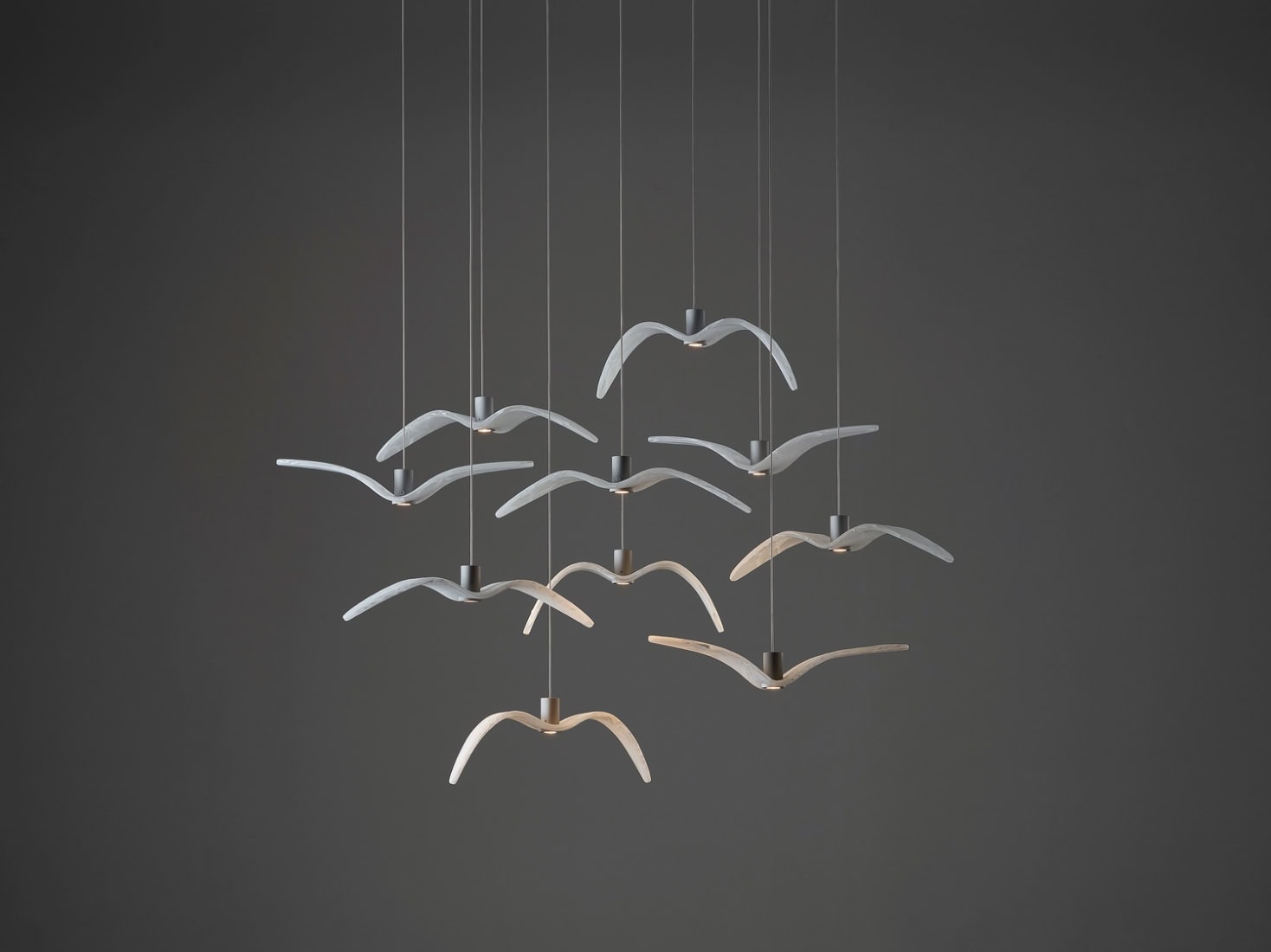 Brokis Night Birds MINI pendants with BROKISGLASS wings soar in a flock formation against a dark grey backdrop.