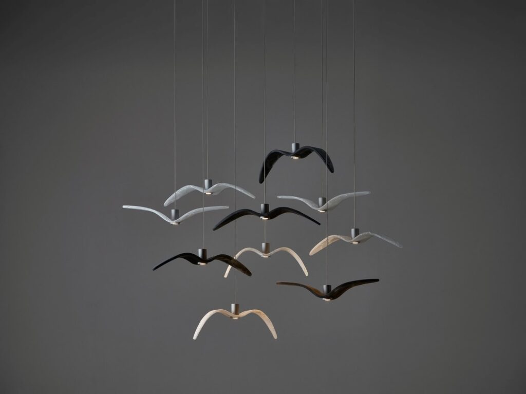 Nine Brokis Night Birds MINI pendants, handblown to resemble birds in flight, float at varied heights, casting a soft glow.