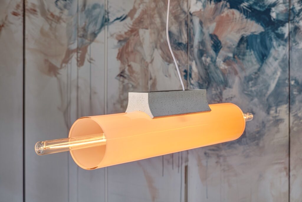 Brokis Overlay Chandelier L in handblown frosted amber glass with a grey accent, set against abstract painted panels.