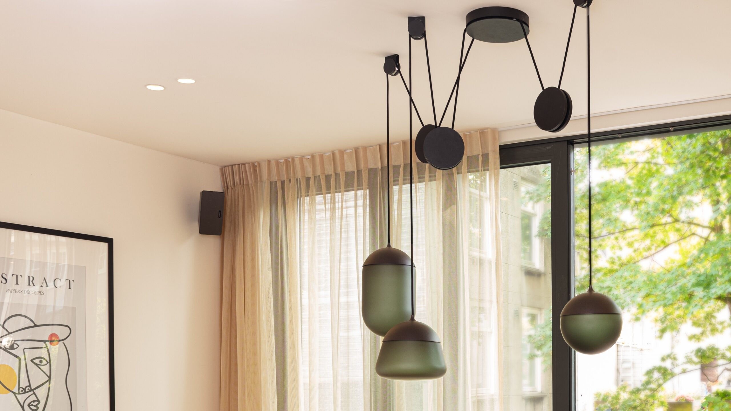 Brokis Planets 3 Set with grey glass shades hang above sheer beige curtains and a framed abstract artwork.