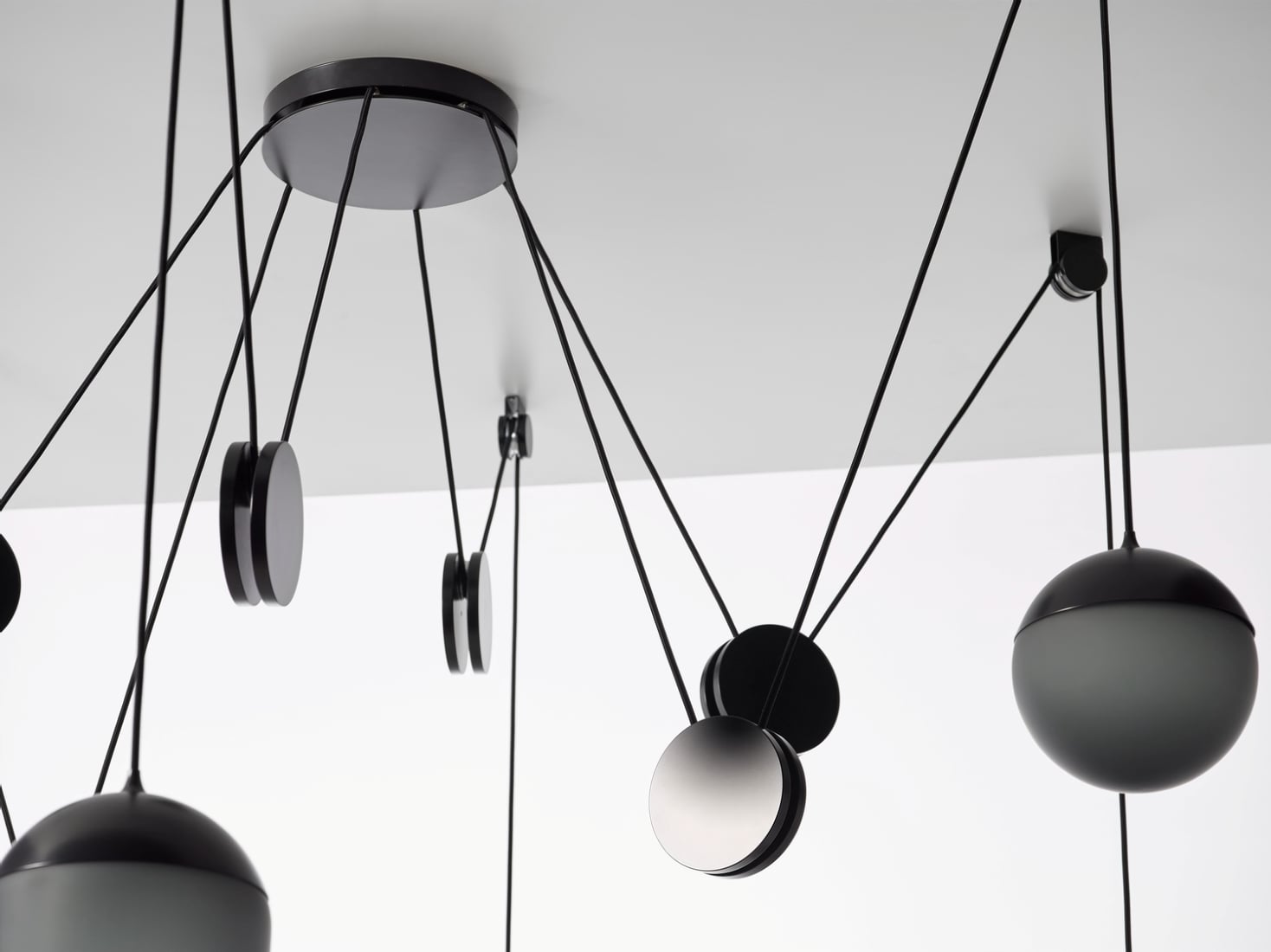 Brokis Planets 6 Set with sculptural black mounts and cords suspends glass orbs in a luxe geometric arrangement.