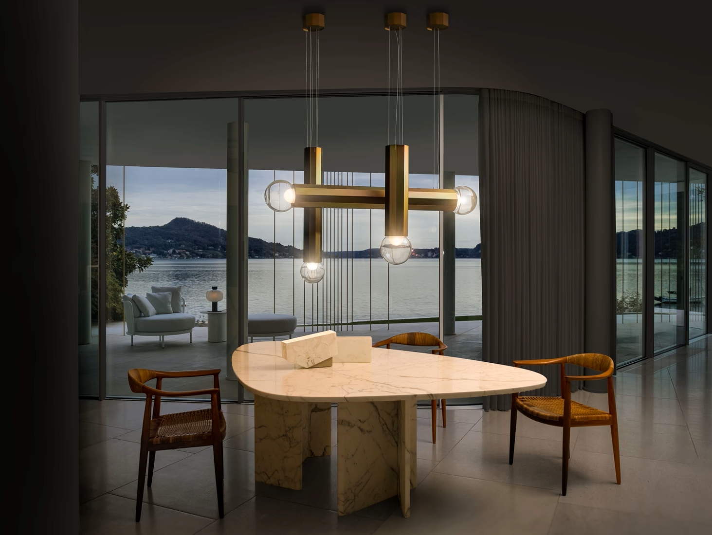 Elegant dining area with cream marble table, four wooden chairs, Brokis Prisma zinc chandelier, and balcony lake views.