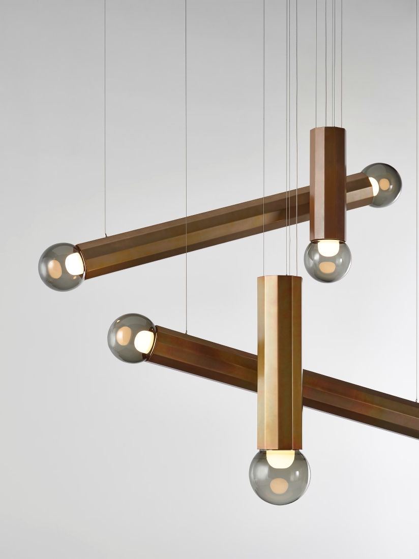 Four Brokis Prisma lights in yellow zinc and grey glass float elegantly on fine wires against a pale backdrop.