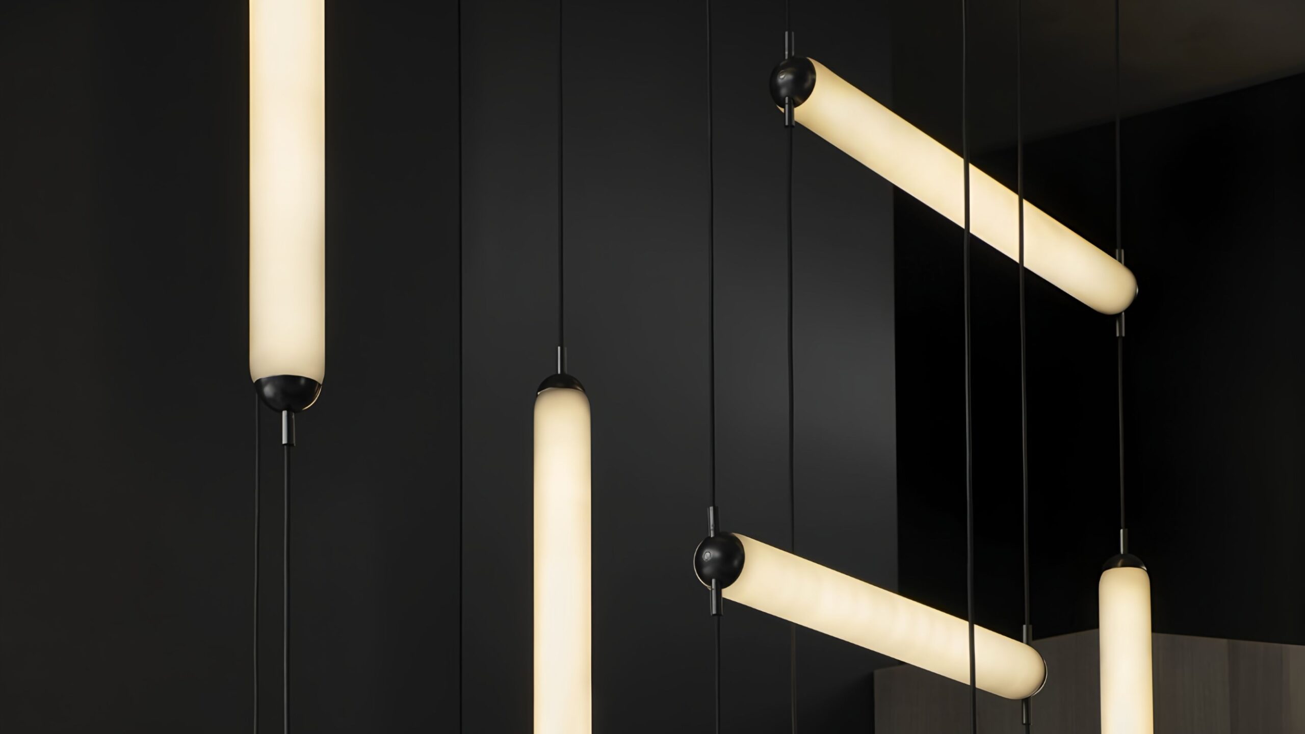 Brokis Puro Single pendants with a warm glow float on matte black, exuding modern luxury and sleek minimalism.