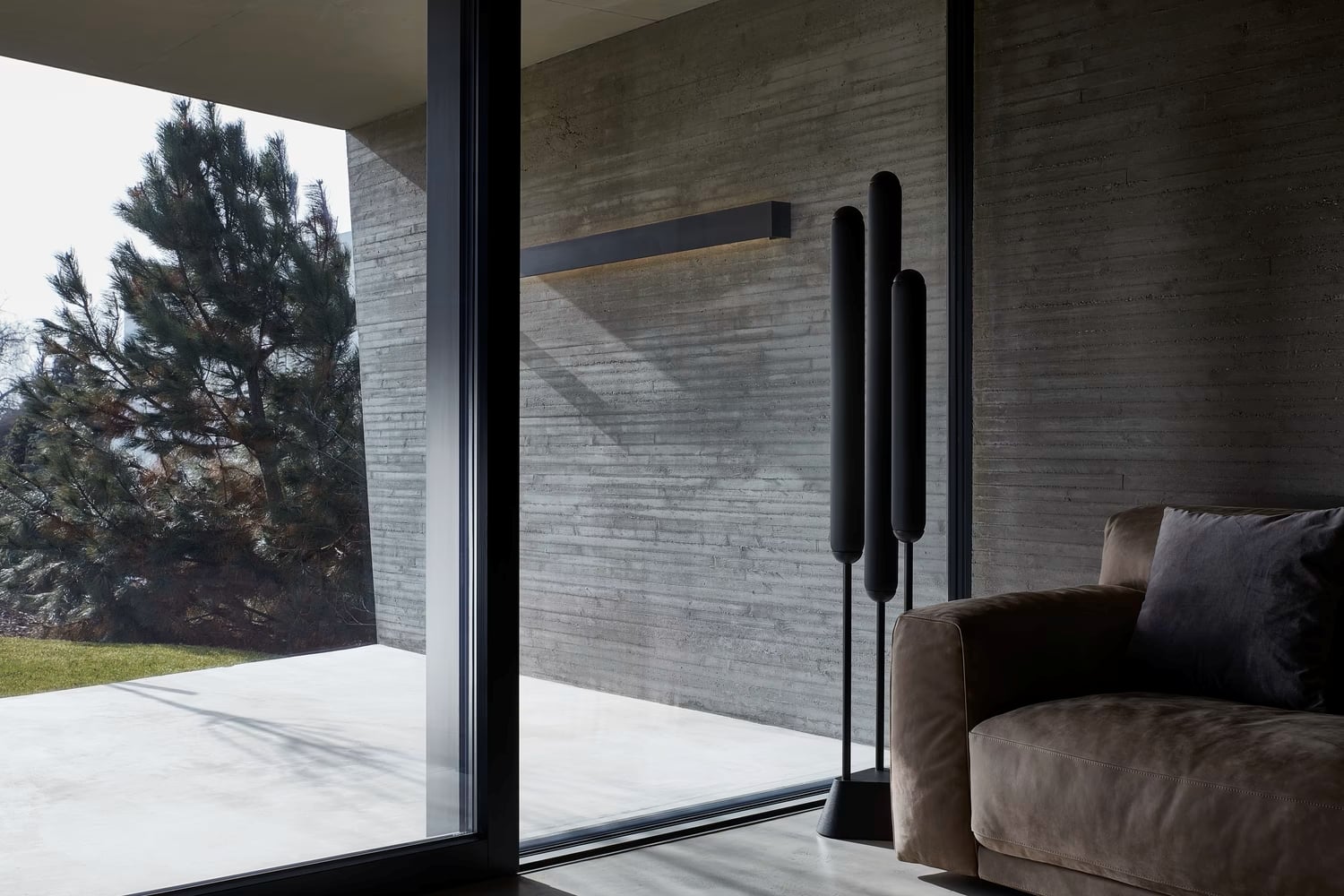 A living room with floor-to-ceiling glass doors, brown sofa, and black Puro Floor 3 Tubes 1550 exuding quiet luxury.