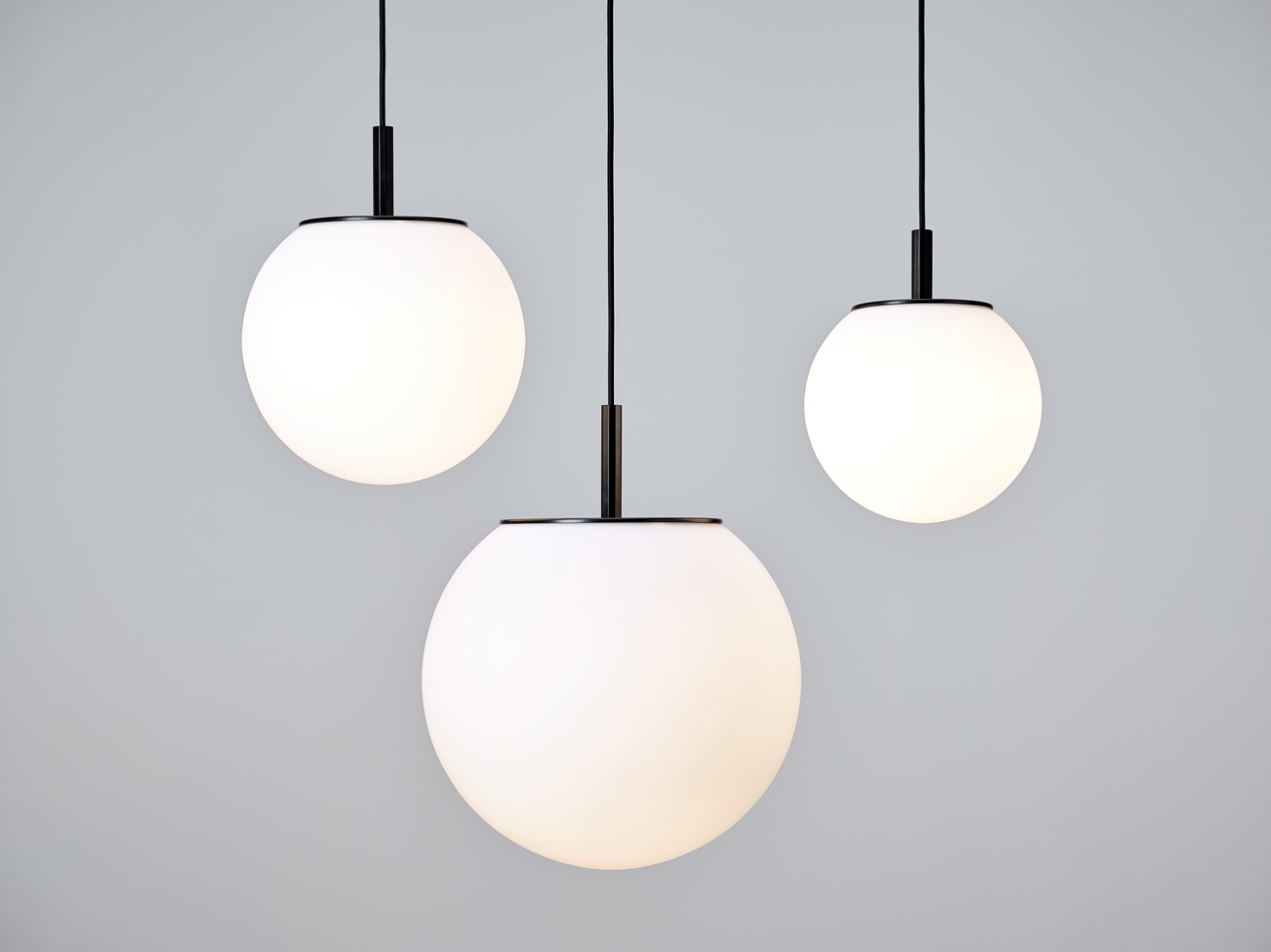 Brokis Sfera pendants with handblown triplex opal glass shades hang at varying heights, exuding modern luxury.