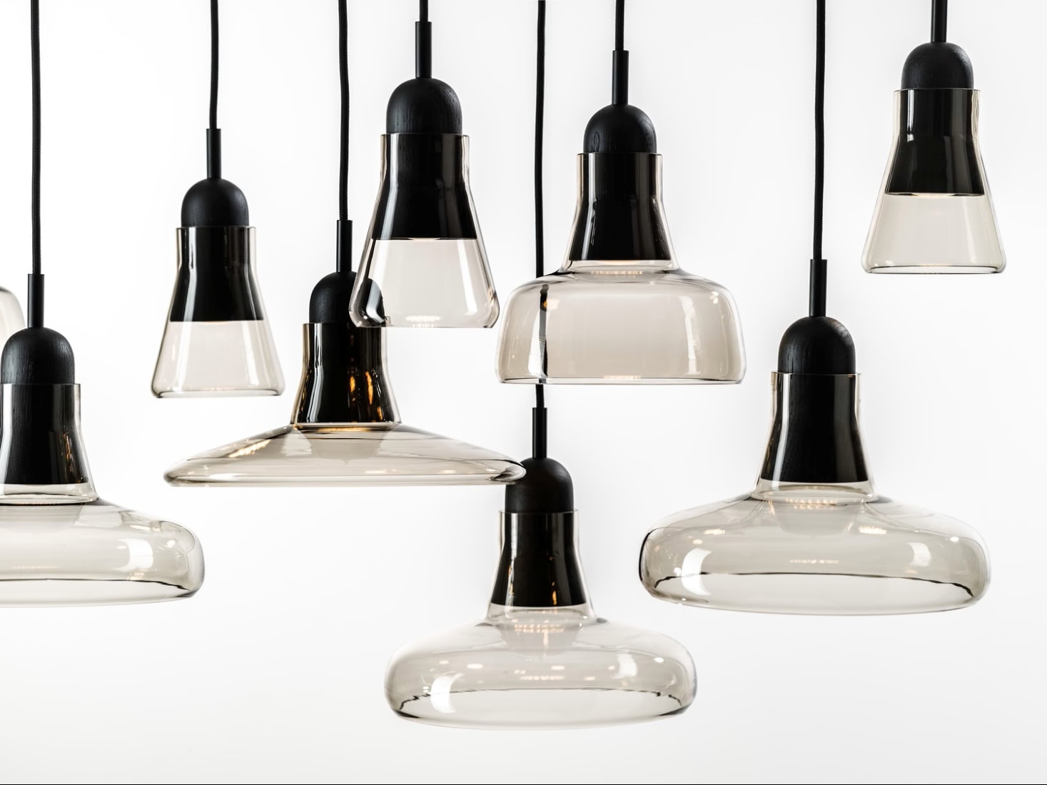 Brokis Shadows pendants with sculptural tinted glass shades hang at varied heights, exuding minimalist luxury.