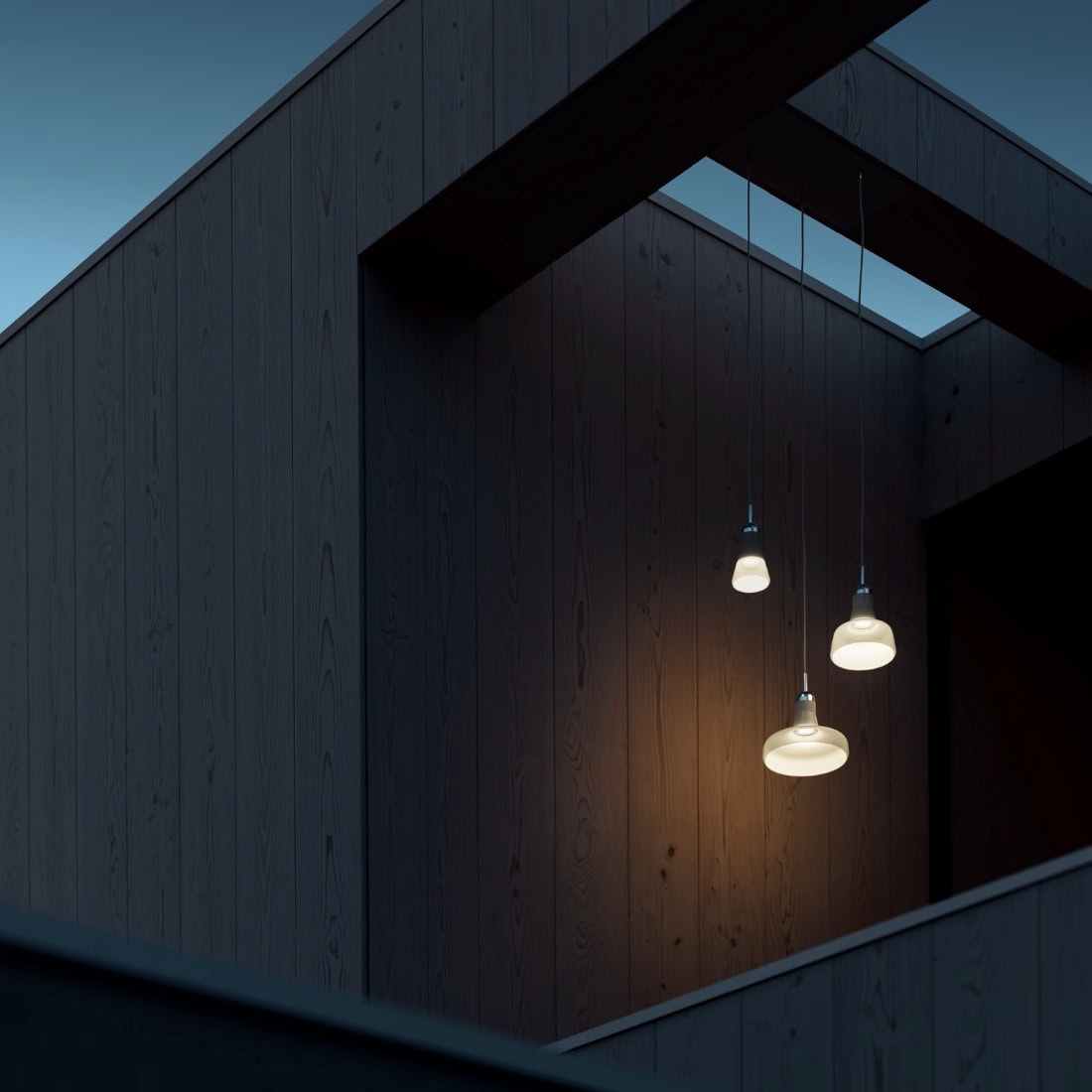 Three Shadows Exterior pendants glow warmly in a minimalist dark wood interior, contrasting cool dusk blues outside.