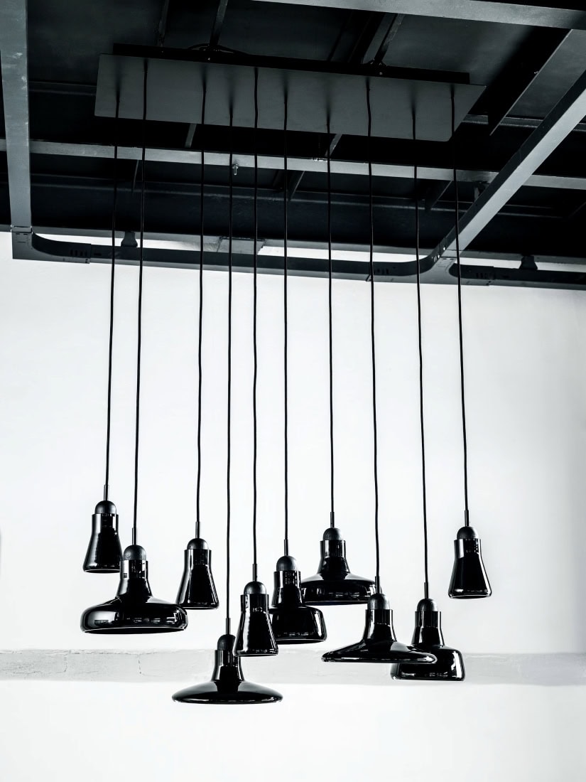 Brokis Shadows black pendants with sculptural forms cascade from a dark ceiling, exuding luxury against crisp white walls.