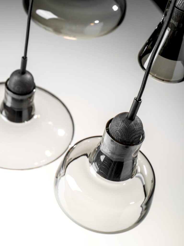 Brokis Shadows pendants in sculptural clear glass with black fittings, casting soft reflections on a pristine white surface.