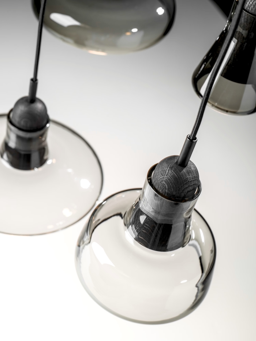 Brokis Shadows pendants in sculptural clear glass with black fittings, casting soft reflections on a pristine white surface.
