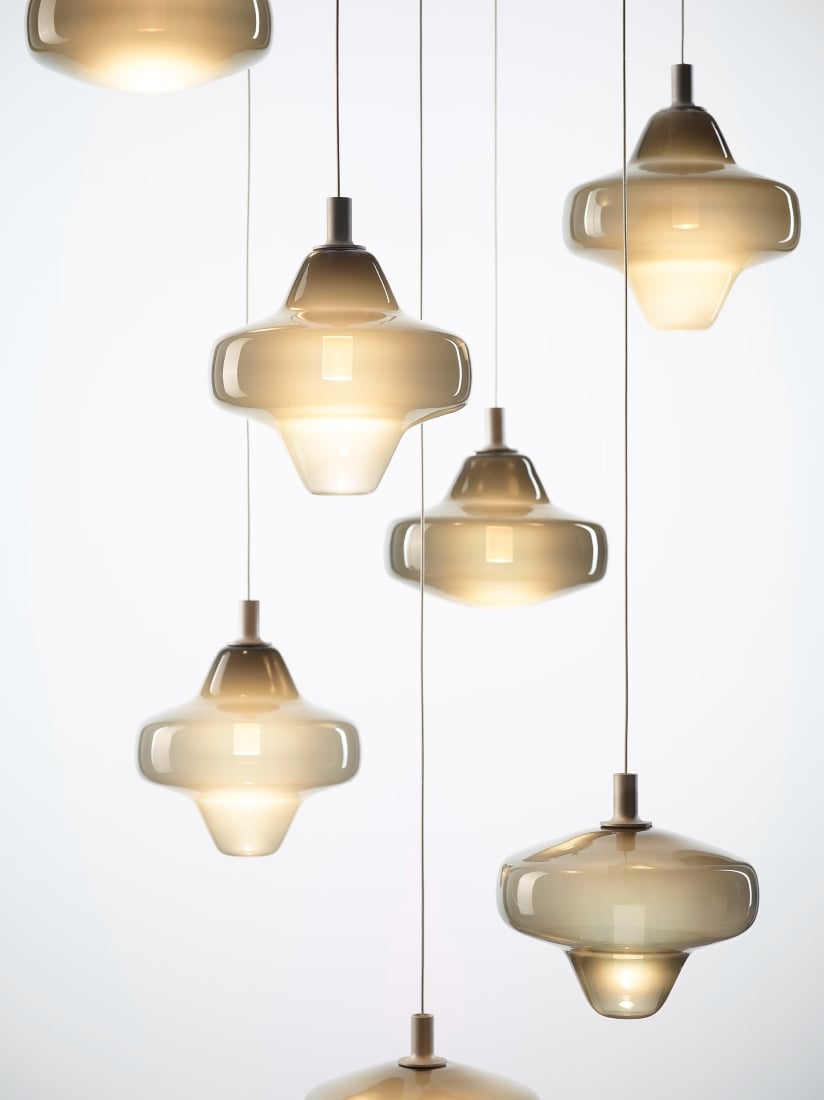 Brokis Starcloud lights with glossy glass shades hang at varying heights, casting a warm, luxe glow.