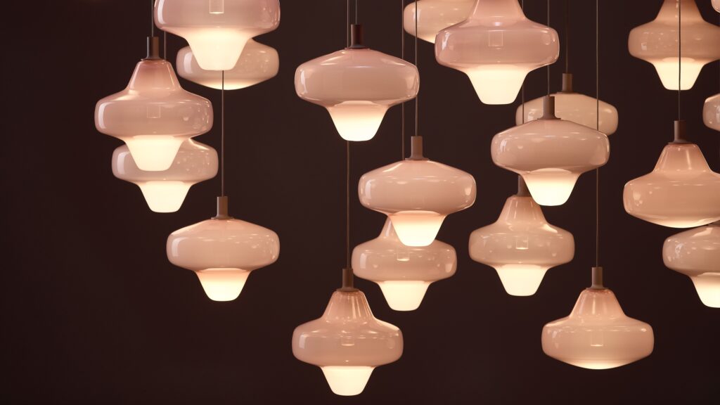 Brokis Starcloud pendants with opaline glass shades glow warmly at varied heights, exuding elegant modern luxury.