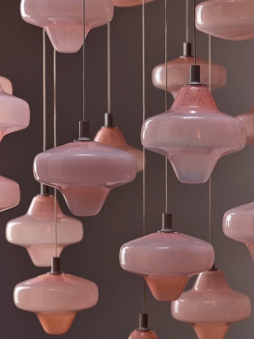 Brokis Starcloud pendant lights in glossy pearl pink glass, suspended at varied heights by fine dark cords.
