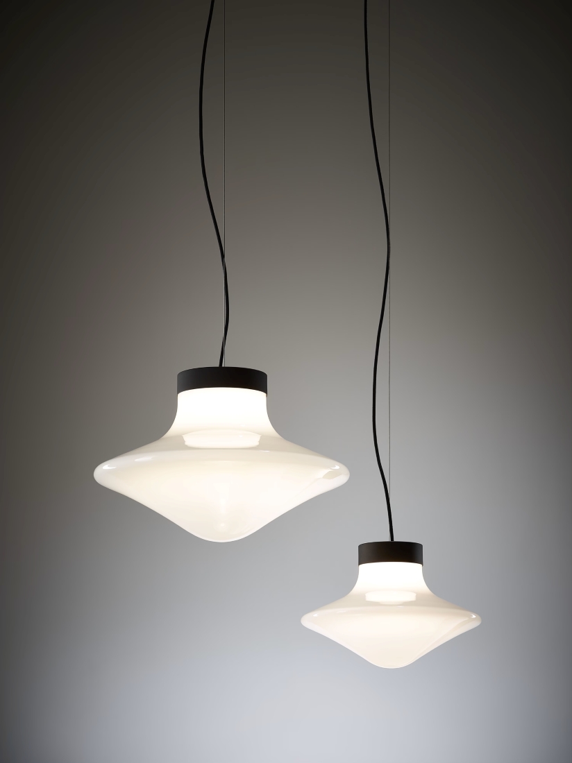 Brokis Trottola pendants in curved white glass cast a soft glow, elevating the minimalist grey interior.