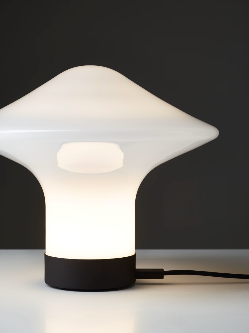 Brokis Trottola Table S with a handblown opaline glass shade and black base casts a luxe glow on a sleek white surface.