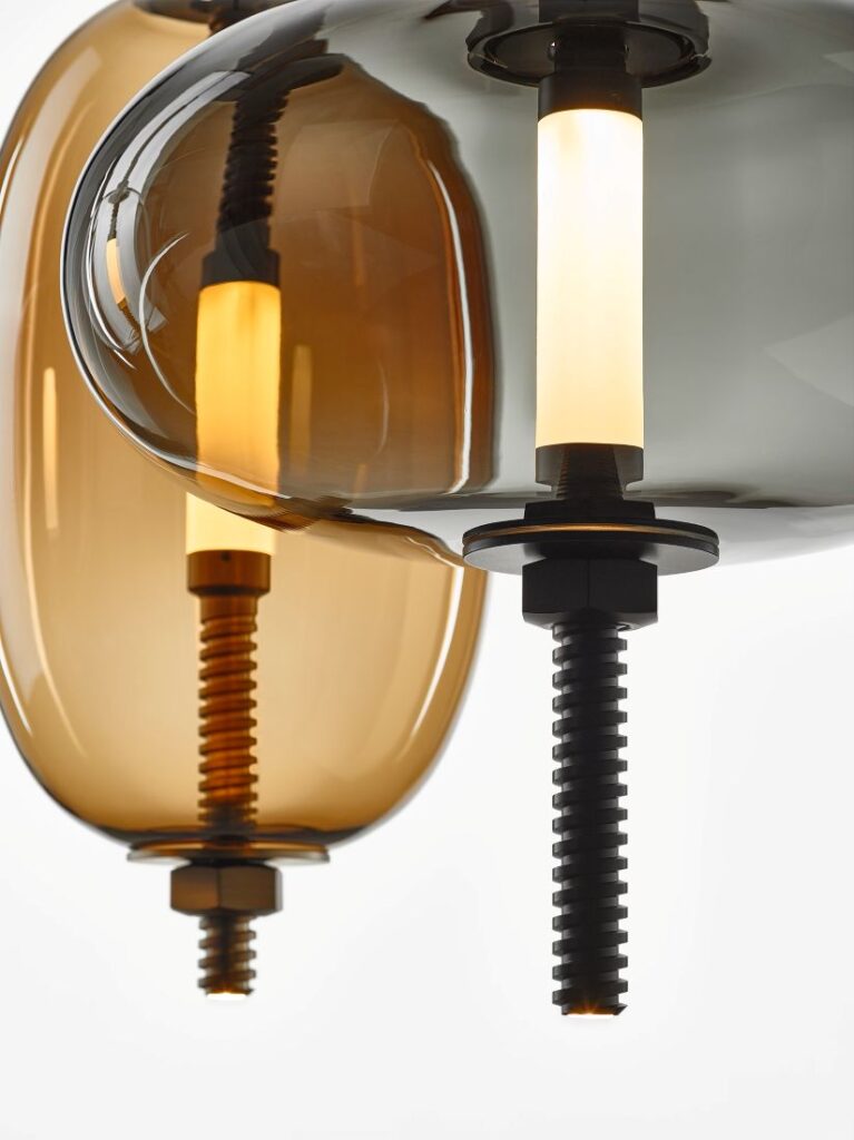 Close-up of Brokis Under Pressure pendants with handblown glass and glowing LED, luxe against a white backdrop.