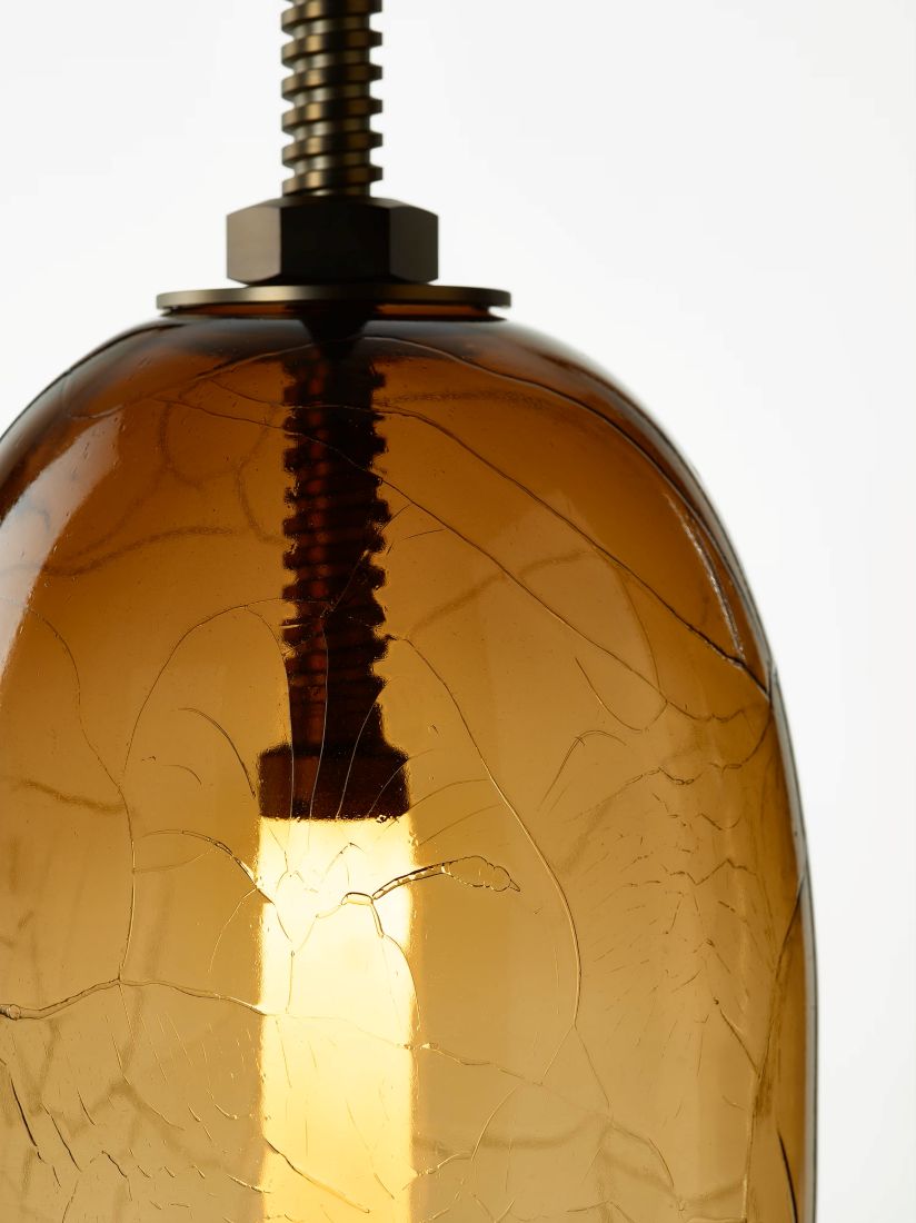 Close-up of Brokis Under Pressure Vertical Little brown glass pendant, with crackled shade, metallic accents, and LED.