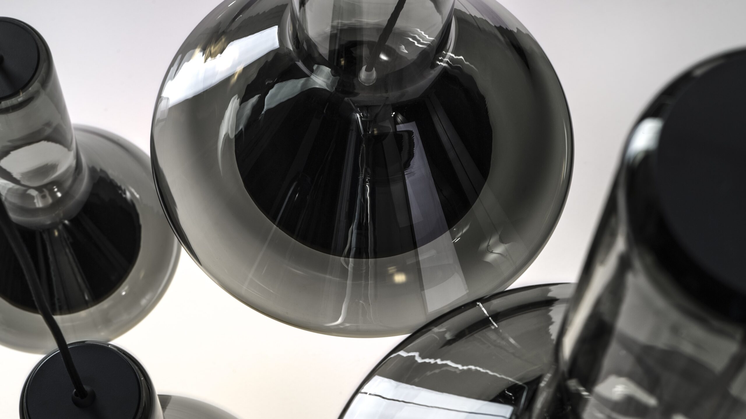 Brokis Whistle pendants with black glass, shimmering against a softly illuminated background.