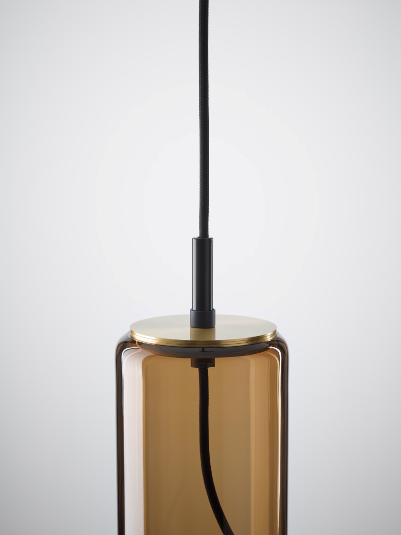 Brokis Whistle pendant with smoke brown fittings hangs elegantly from a black flex on a white backdrop.