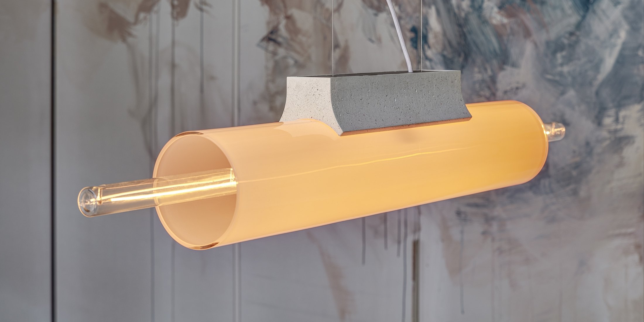 Brokis Overlay Chandelier L with hand-blown amber glass and a concrete top emits a warm glow before abstract art panels.