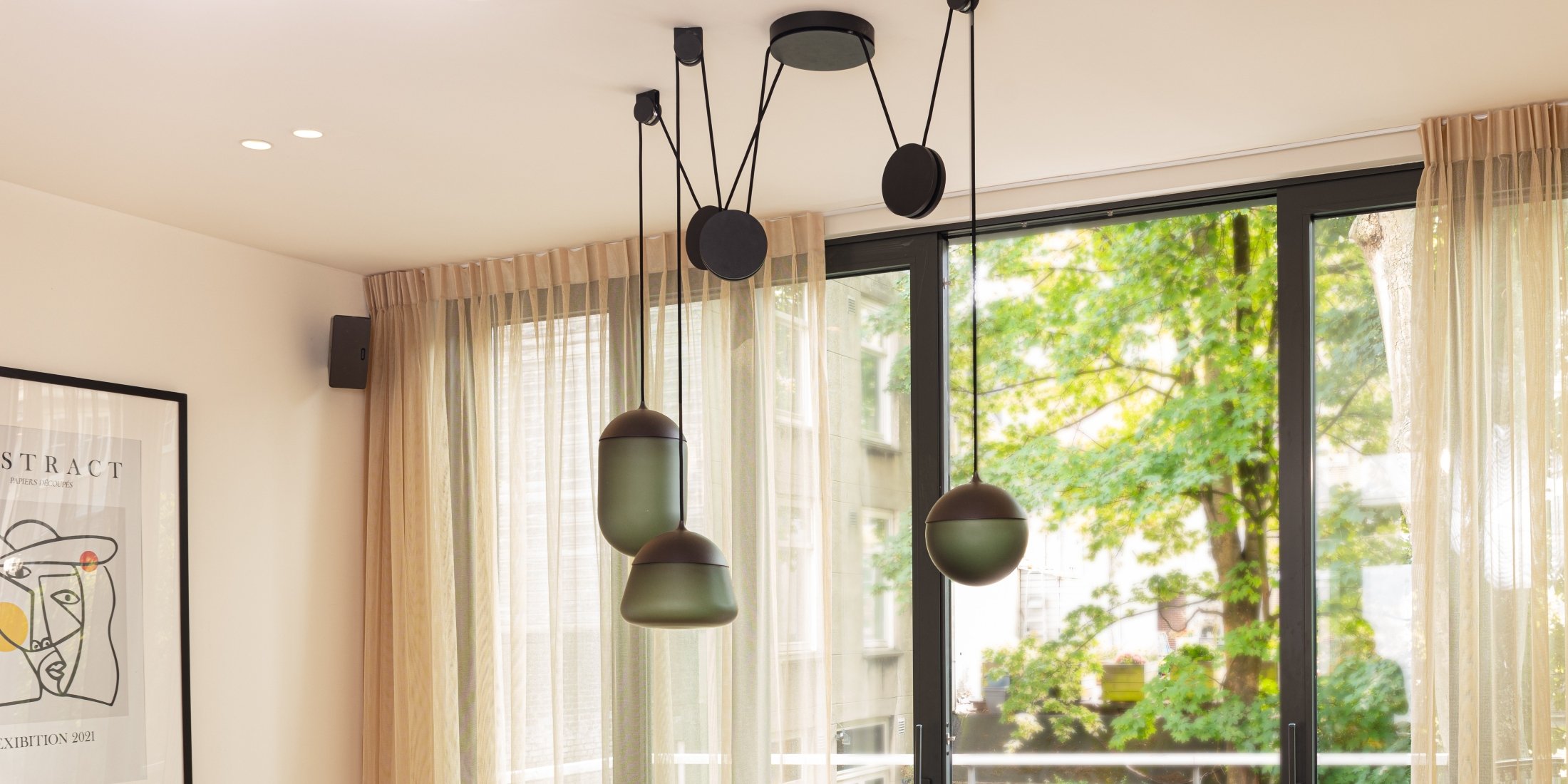 Brokis Planets 3 Set in sculptural grey glass grace a white ceiling; sheer curtains frame lush garden views.