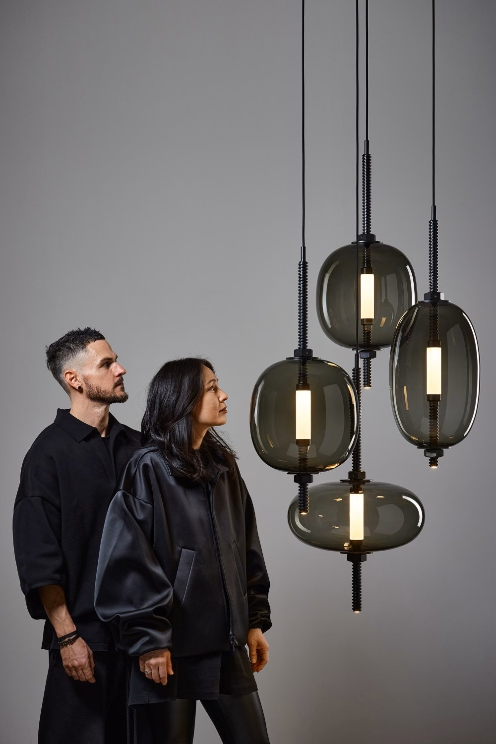 Designers Boris Klimek and Lenka Damová admire Brokis Under Pressure pendants suspended at varying heights.