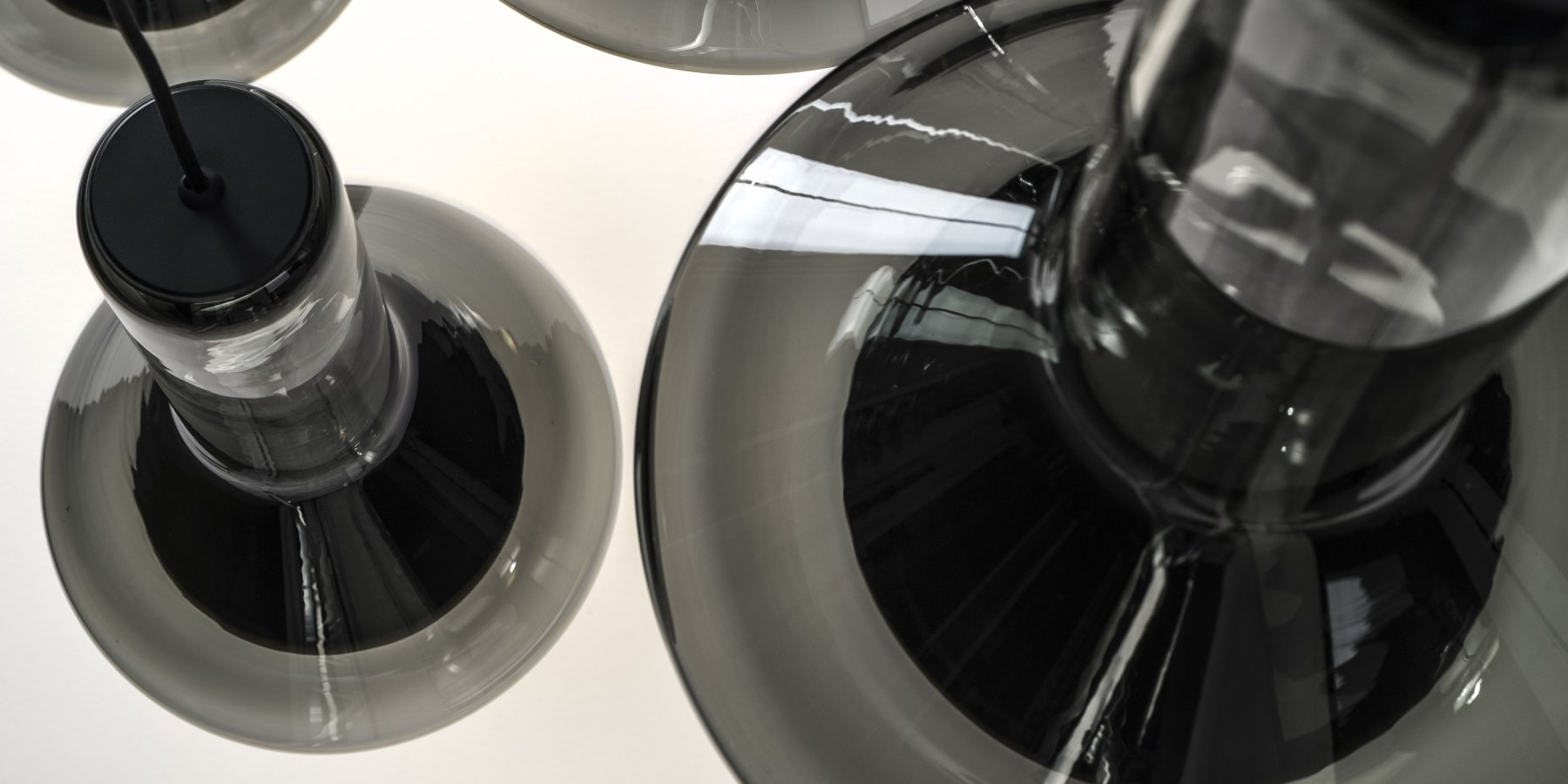 Brokis Whistle smoke grey glass pendants showcase handblown crystal forms and luxe reflections on white.