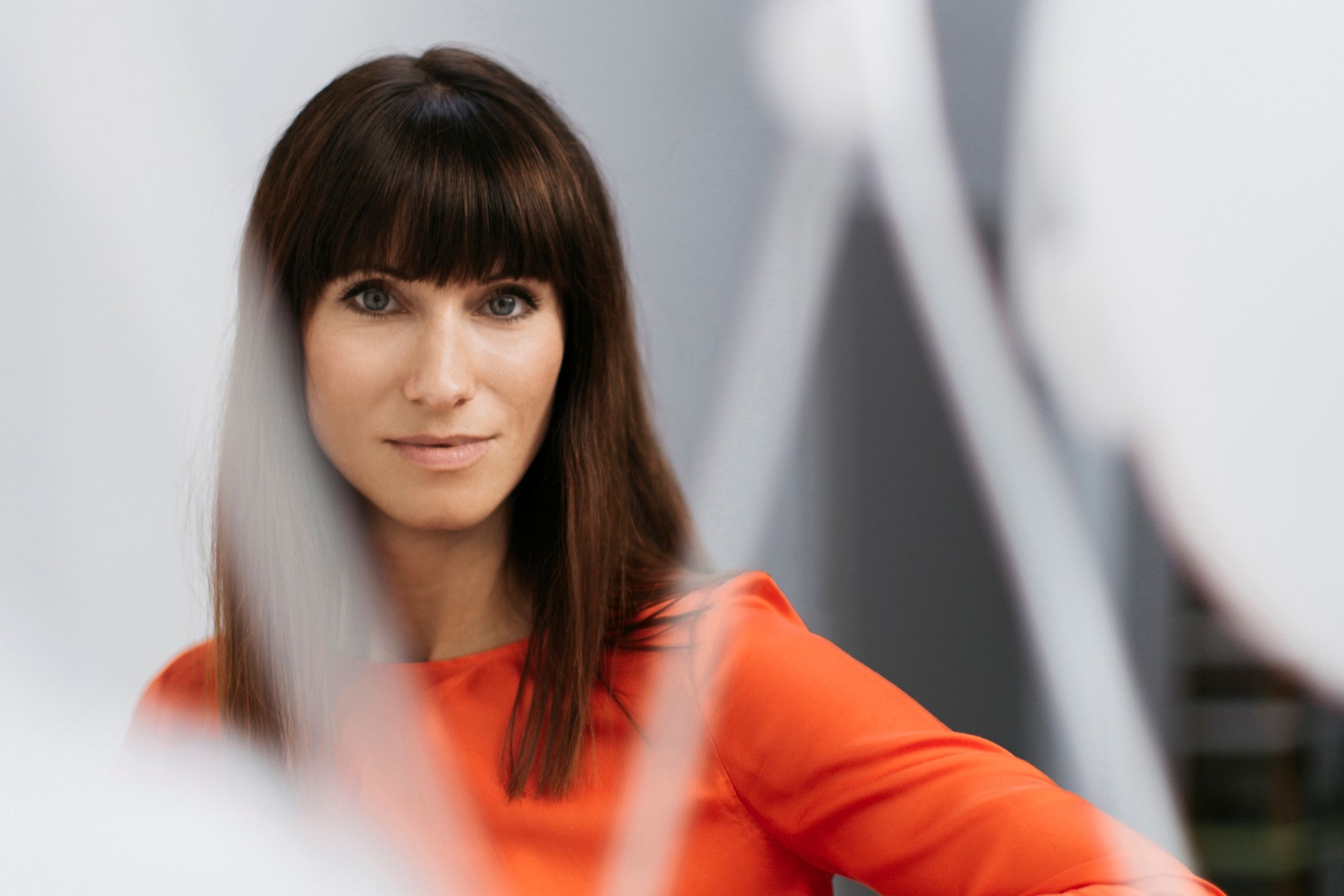 Brokis art director Lucie Koldova gazes ahead, set against a soft, modern backdrop of luminous white forms.